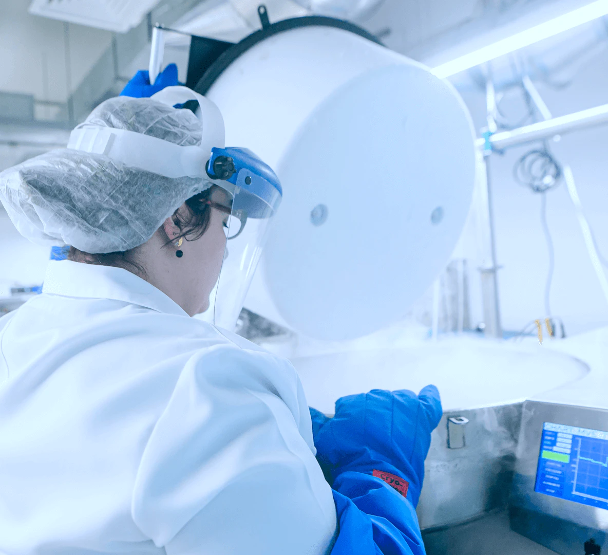 Técnico de laboratório com equipamentos de proteção individual trabalhando em capela de fluxo laminar para processamento e congelamento de sêmen, preservando fertilidade masculina