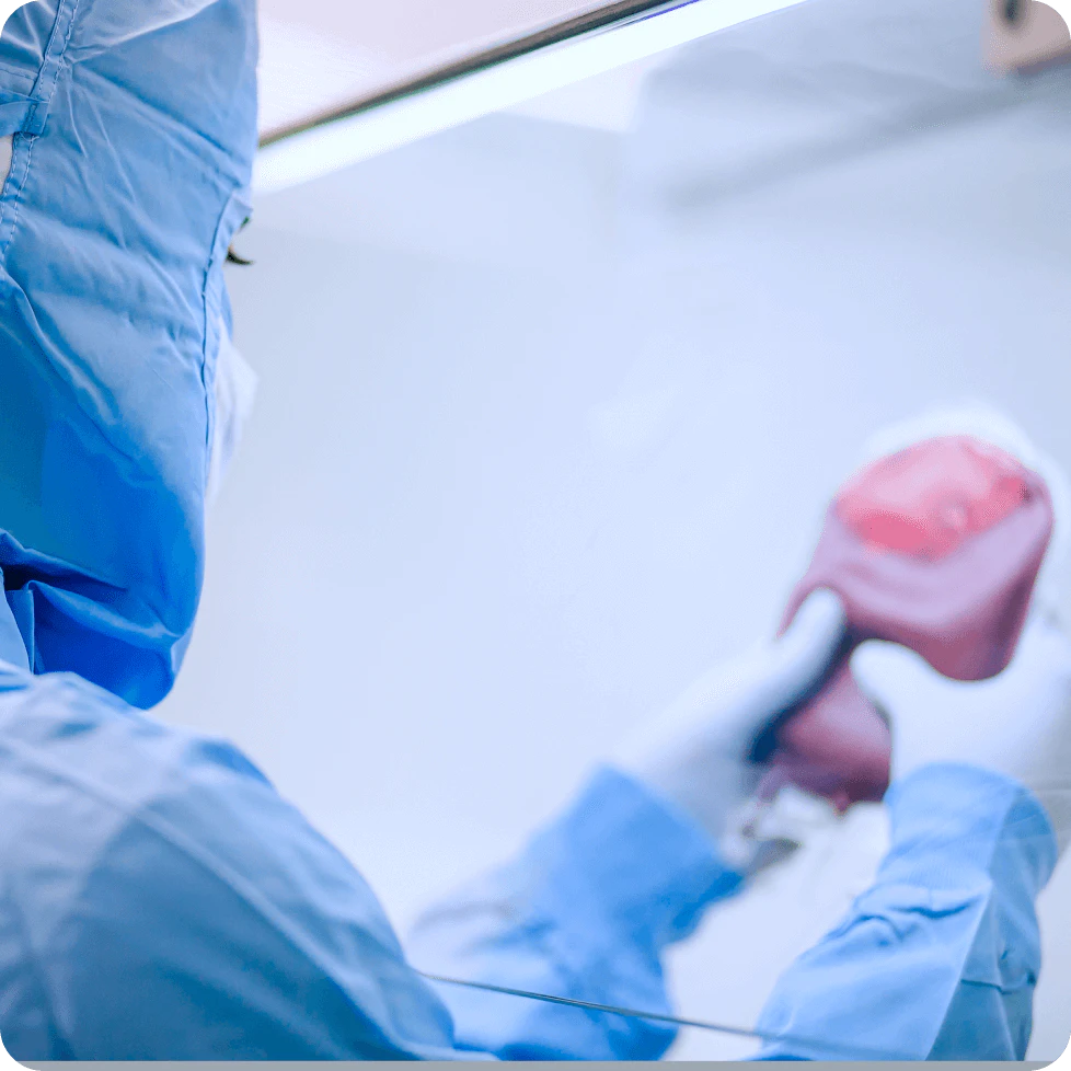 Técnico de laboratório usando uniforme azul manuseando equipamento criogênico rosa para armazenamento de células-tronco de cordão umbilical em ambiente controlado de biopreservação com vapor de nitrogênio líquido