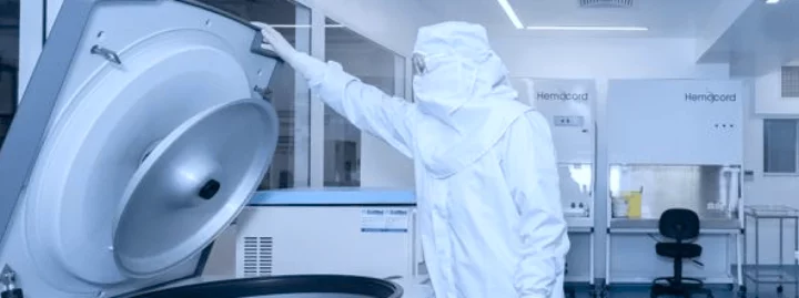 Profissional usando traje de proteção completo branco operando centrífuga de grande porte em laboratório de processamento Hemocord com ambiente controlado e padrões GMP para tratamento de células-tronco de cordão umbilical